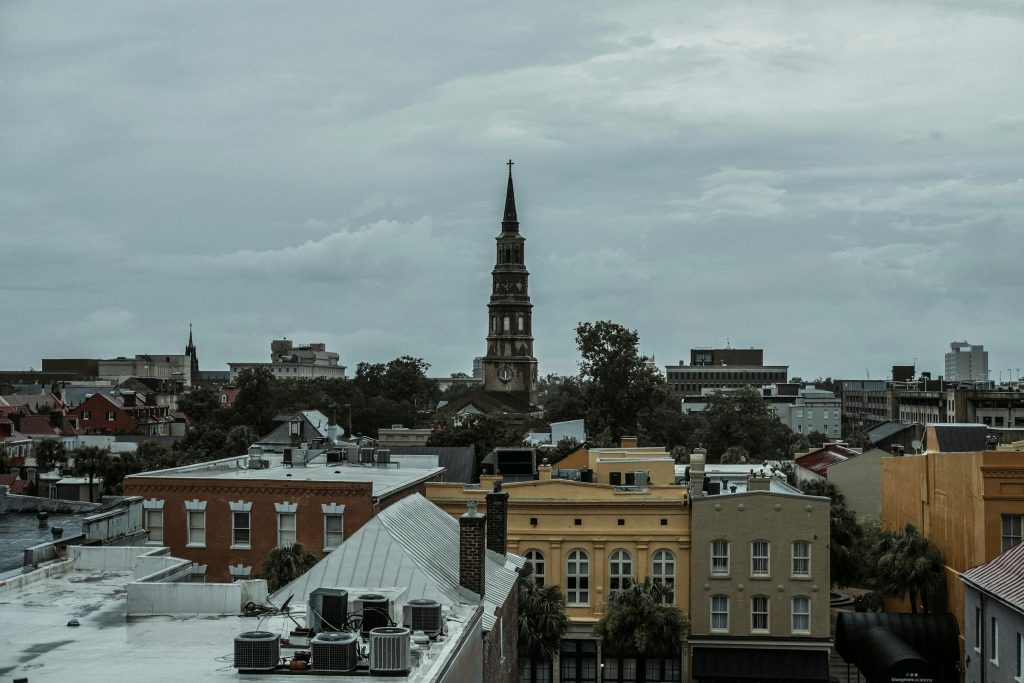 A picturesque view of Charleston, SC, featuring a historic church tower amidst vibrant buildings.