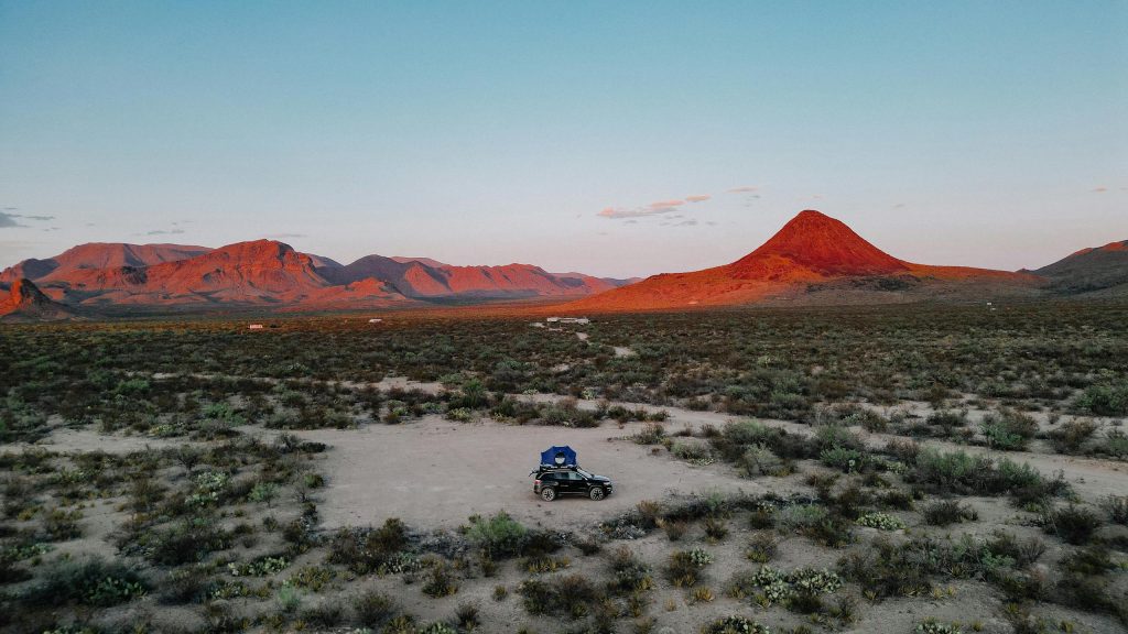 Aerial view of a car camping setup in Terlingua, Texas at sunset with stunning mountain vistas.