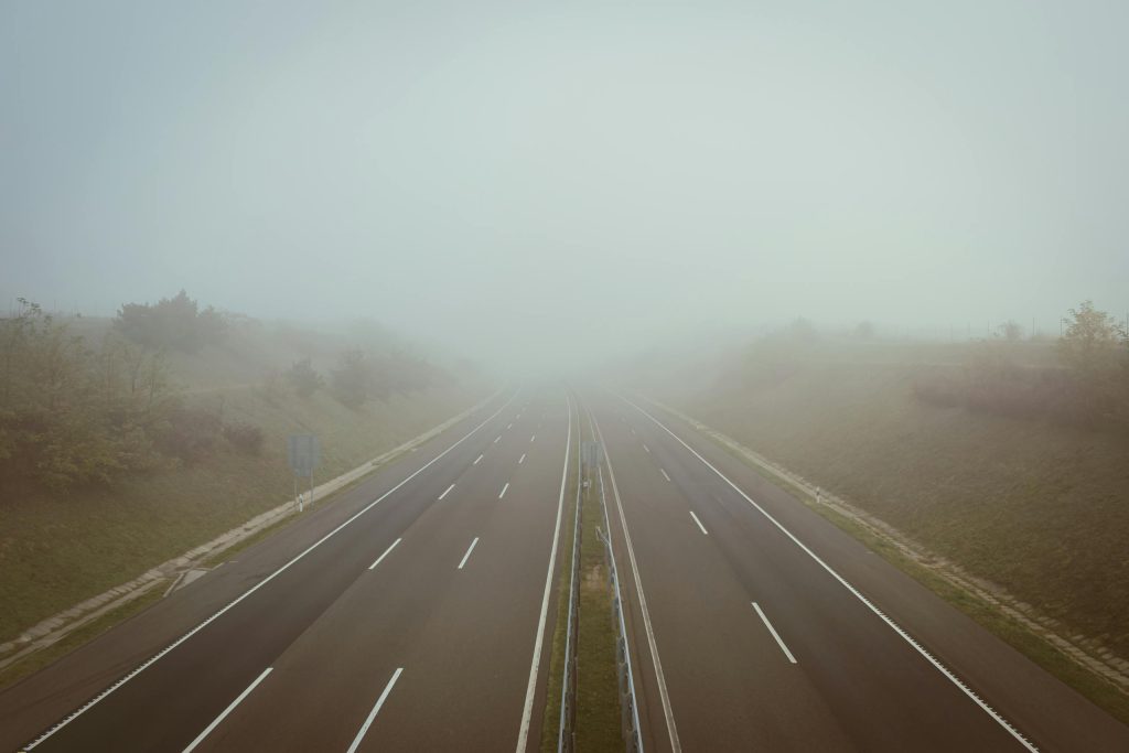 An empty highway engulfed in thick fog, creating a serene and mysterious atmosphere.