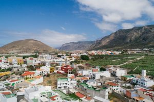 Charming Spanish village with colorful houses and surrounding mountains under a clear blue sky.