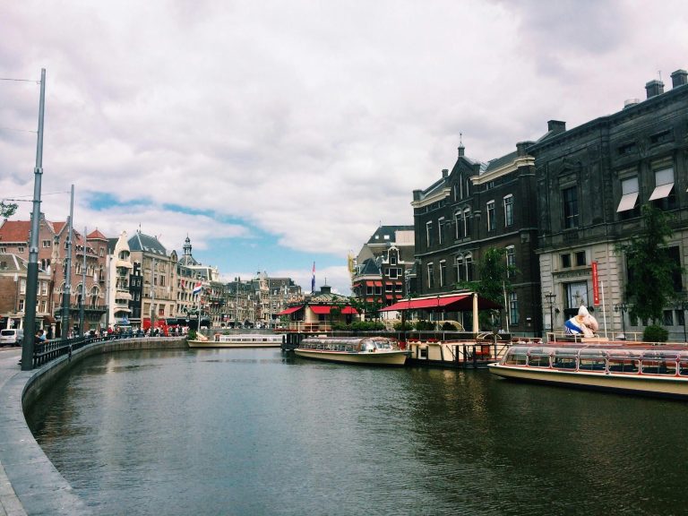 Discover Amsterdam's picturesque canal and historic architecture, featuring tour boats and charming buildings.
