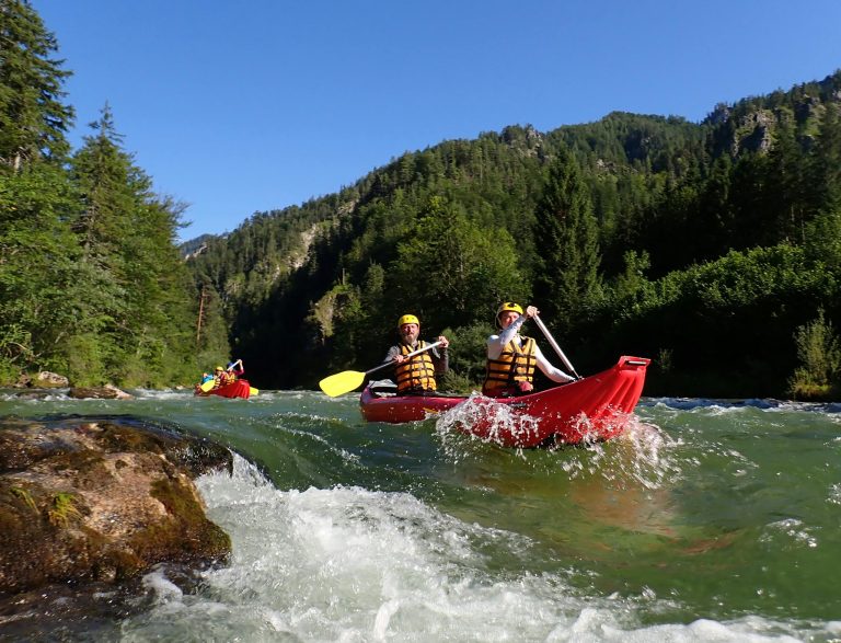 Exciting kayaking adventure on fast-flowing mountain river with lush greenery around. Perfect for thrill-seekers.
