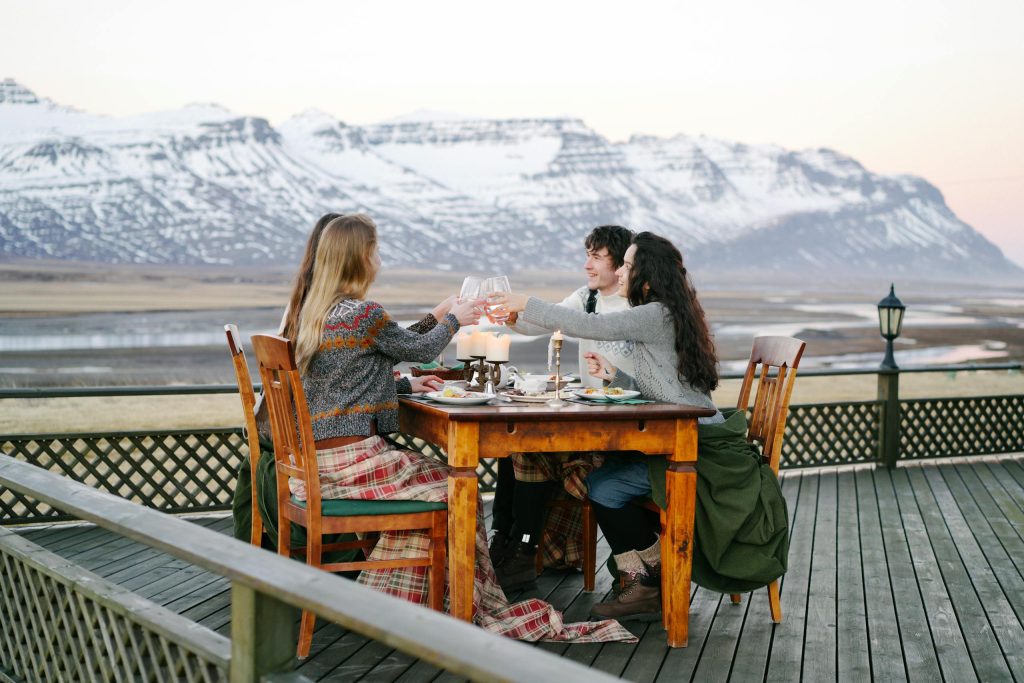 Friends enjoy outdoor dining with a breathtaking view of snowy mountains.