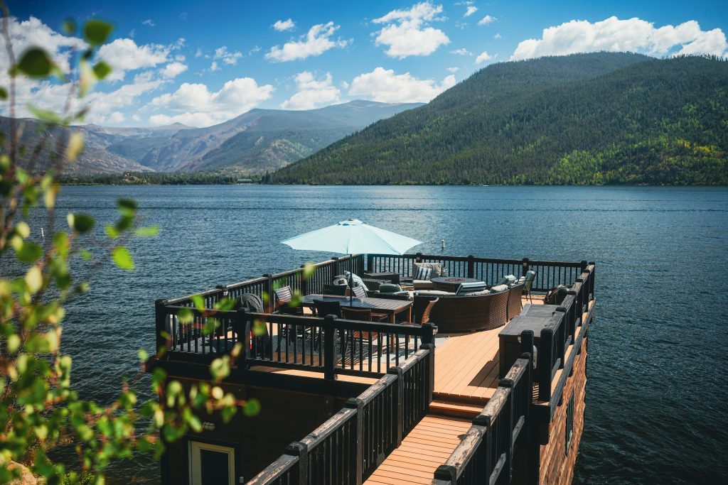 Relaxing lakeside deck view at Grand Lake, Colorado, with mountain backdrop and blue sky.