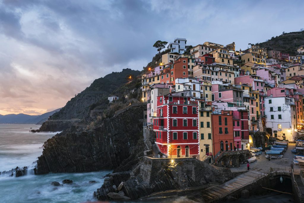 Scenic view of Riomaggiore's vibrant houses on a cliffside at sunset, Liguria, Italy.