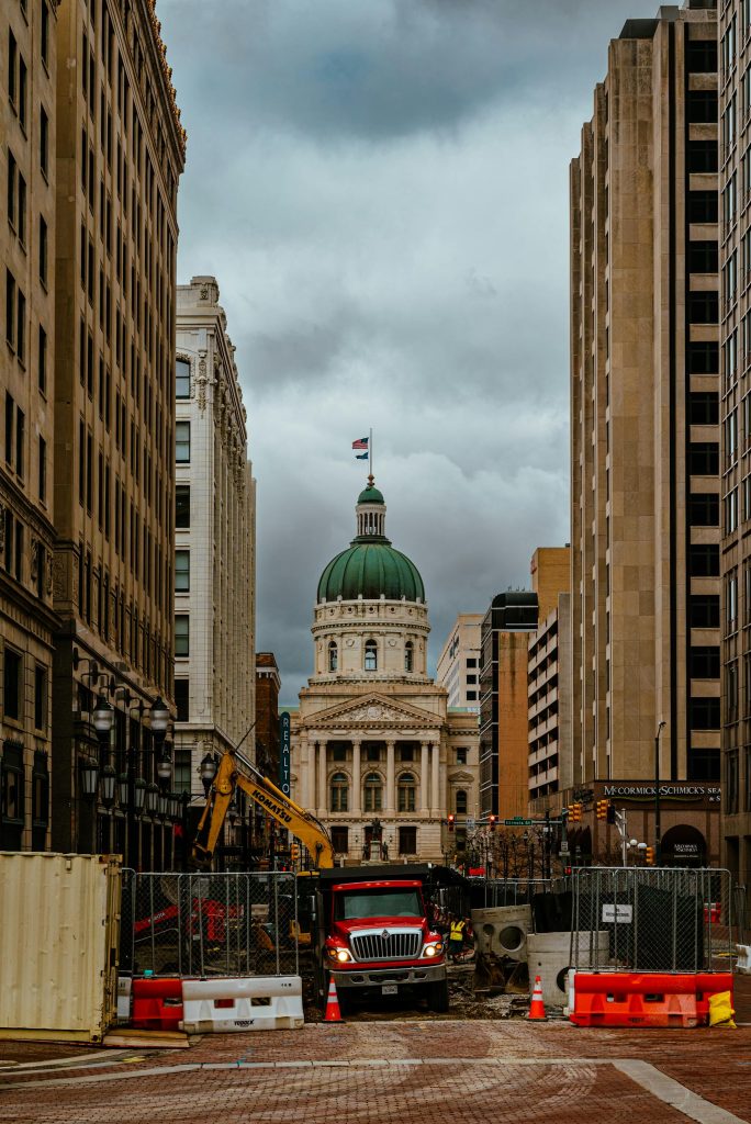 Street construction in Indianapolis with iconic architecture and cloudy sky.