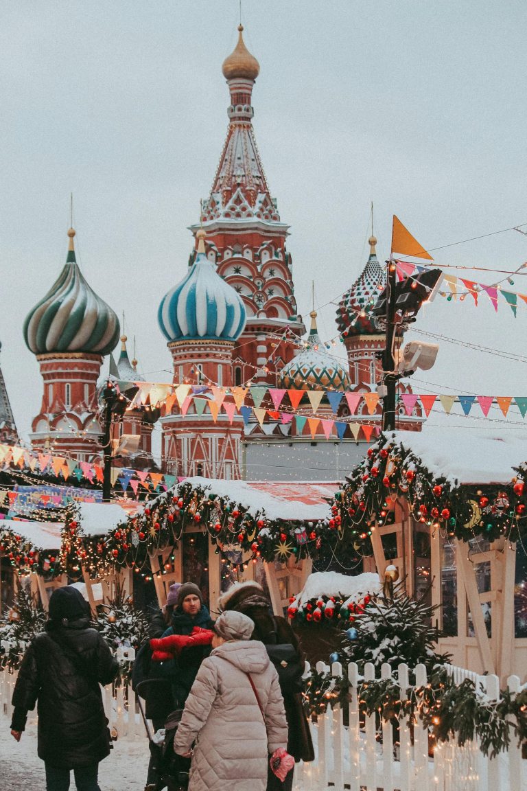Tourists enjoy a winter market near St. Basil's Cathedral with festive decorations and snow.