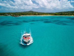 A boat navigates the turquoise Caribbean Sea near Corn Islands, offering a serene view of the Nicaraguan coastline.