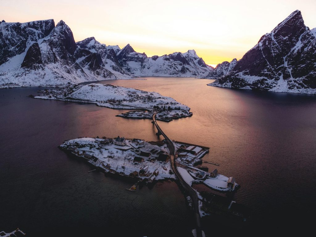 A breathtaking winter sunset over the snow-covered islands and mountains of Moskenes, Norway.