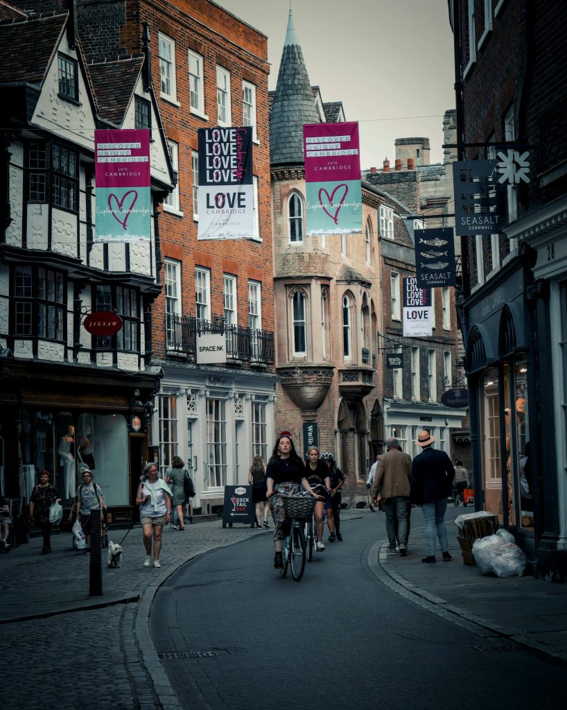 A bustling street in Cambridge with cyclists and pedestrians amidst historic architecture.