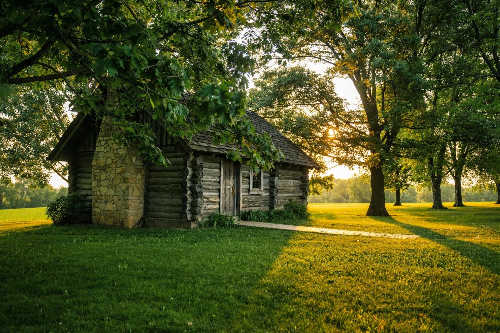 A charming log cabin nestled among trees with a beautiful sunset glow in Lund, Wisconsin.