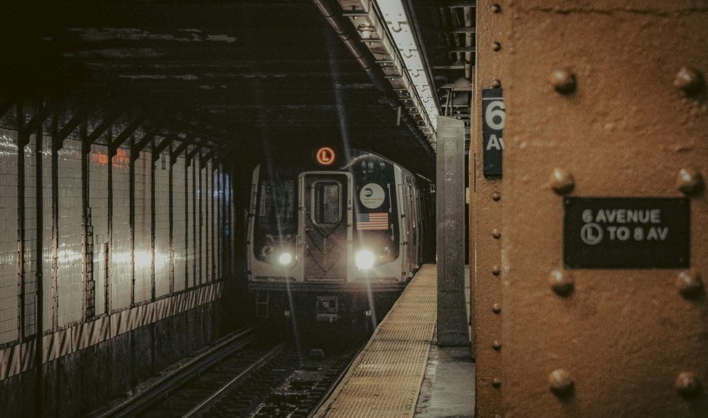 A New York City subway train approaching the platform at 6th Avenue station at night.