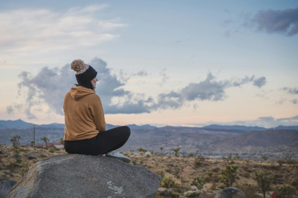 A person sitting on a rock enjoying the scenic desert view in Joshua Tree, CA.