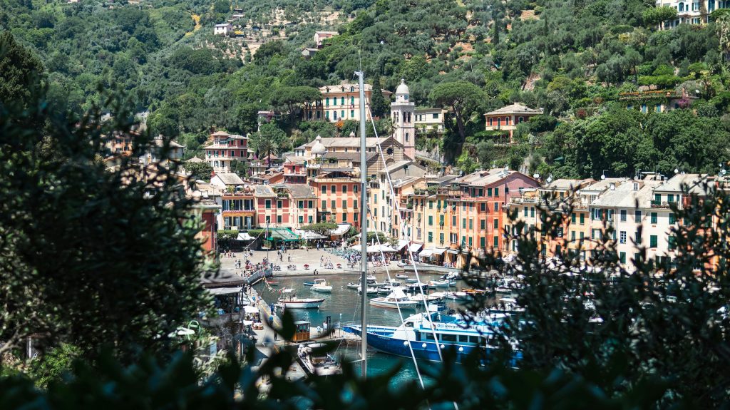 A picturesque view of Portofino's colorful harbor in spring, surrounded by lush greenery and vibrant buildings.