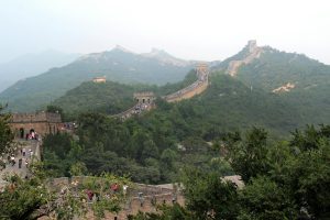 A scenic view of the Great Wall of China stretching over lush green hills in Beijing.