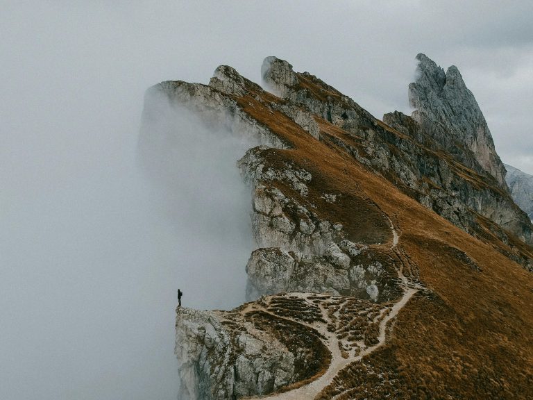 A solitary figure on the misty cliffs of the Dolomites in Italy, an epic autumn landscape.