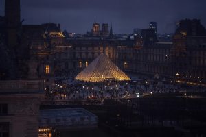 A stunning evening shot of the Louvre Pyramid in Paris, illuminated against the night.