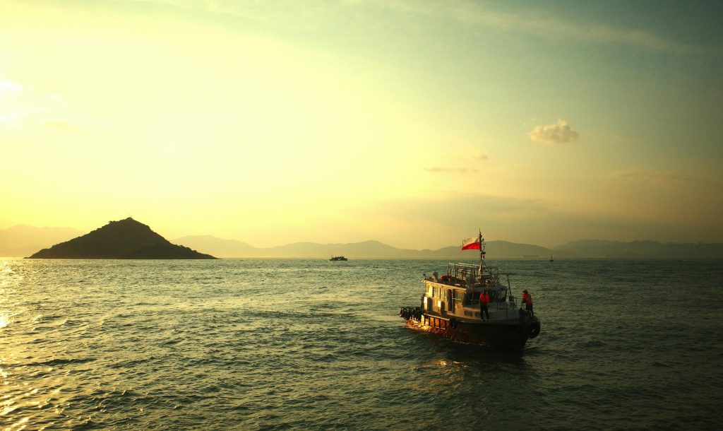 A tranquil boat ride at sunset near Hong Kong Island, with golden water reflections.