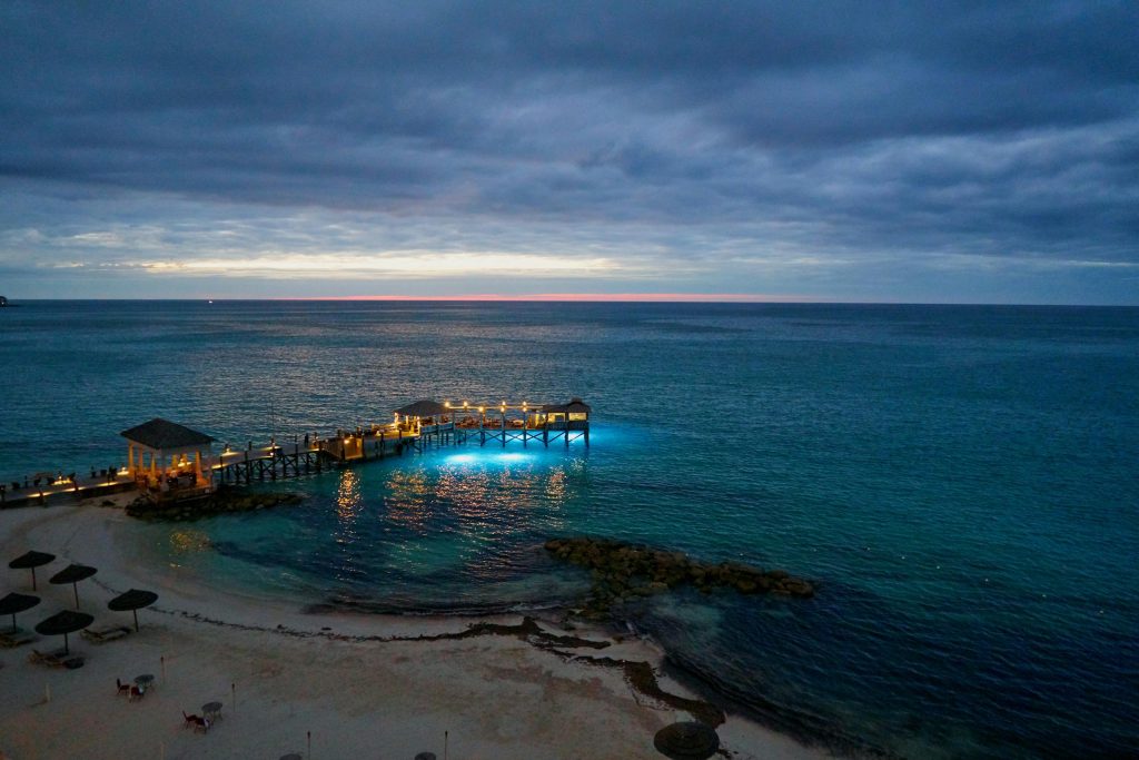 A tranquil seascape at twilight with a pier illuminated over Nassau's blue waters.