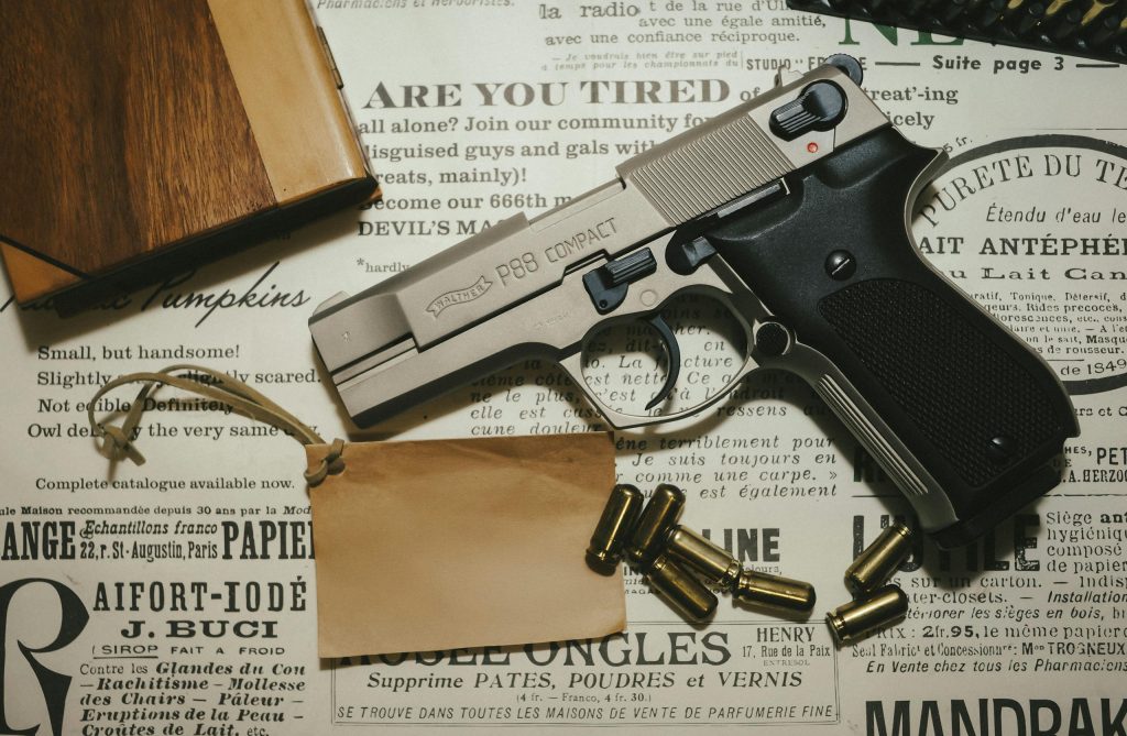 একটি Walther P99 কমপ্যাক্ট পিস্তল যা বুলেট সহ প্রদর্শিত এবং একটি কাঠের বাক্স পুরানো কাগজে।