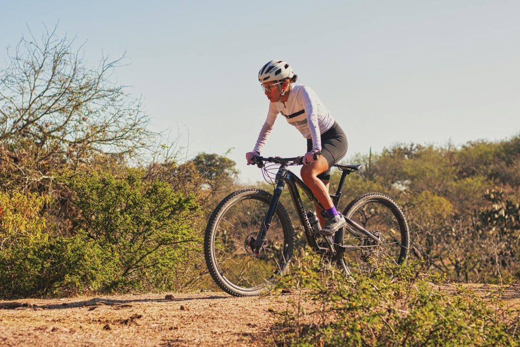 A woman mountain biking on a sunny day in the Mexican outdoors, surrounded by nature.
