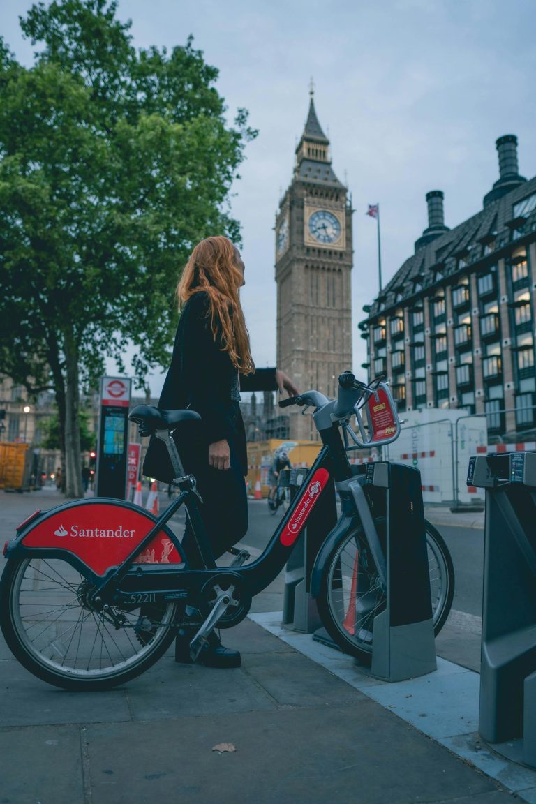 A woman renting a Santander bike near Big Ben, London, showcasing urban mobility and iconic landmarks.
