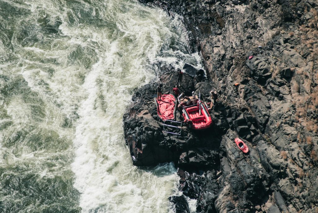 Adventure scene of red rafting gear on rocky riverside, from above.