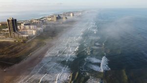 Aerial photograph of South Padre Island, Texas showcasing misty coastal view with buildings and waves.