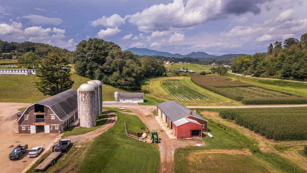 Aerial view of a picturesque farm with silos and barns in the lush North Carolina countryside.