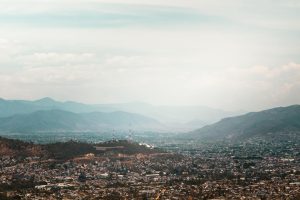 Aerial view of Oaxaca City, Mexico, surrounded by mountains and a vast sky, perfect for travel and nature enthusiasts.