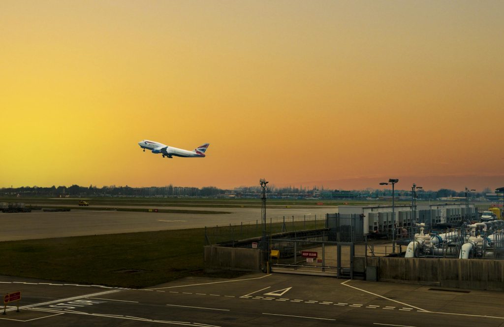 Airplane ascending during sunset at Heathrow Airport, capturing the vibrant sky.