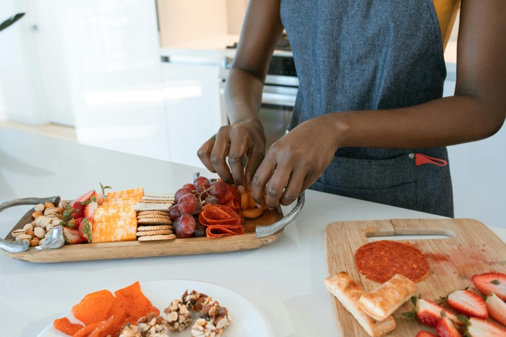 Artisan charcuterie board preparation with meats, cheeses, and fruits in a home kitchen.
