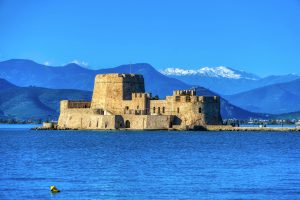 Beautiful daytime view of Bourtzi Castle in Nafplio, Greece, with mountains and sea.