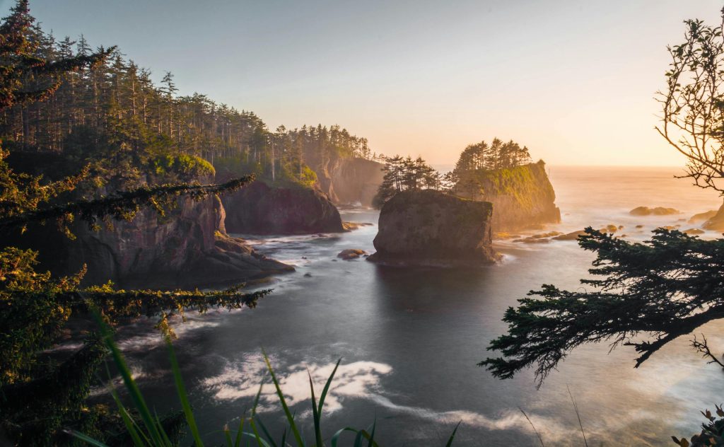 Breathtaking view of Cape Flattery's coastline at sunset, featuring rugged cliffs and serene waters.