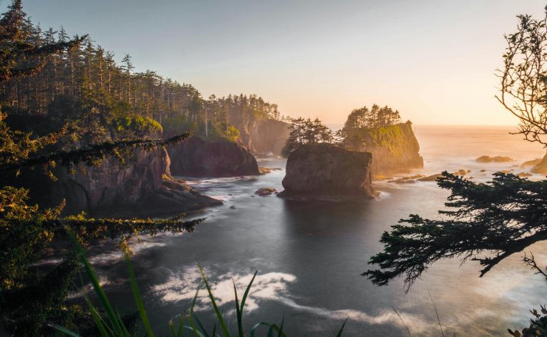Breathtaking view of Cape Flattery's coastline at sunset, featuring rugged cliffs and serene waters.