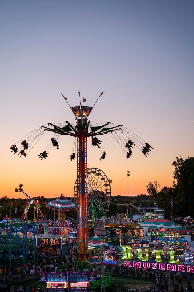 Colorful fairground rides and attractions at sunset in Boise, ID, creating a lively and exciting atmosphere.