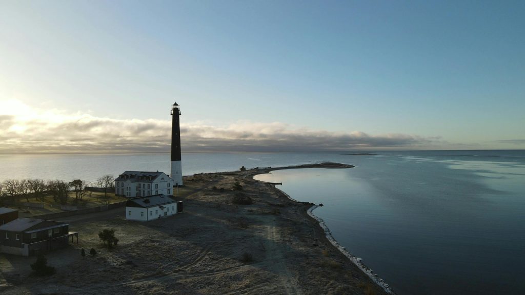 Dramatic view of a lighthouse standing tall on the serene coast of Saaremaa, Estonia.
