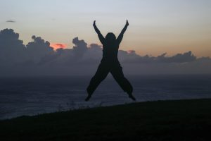 Dynamic silhouette of a person jumping in Saint Kitts at sunset with an ocean view.