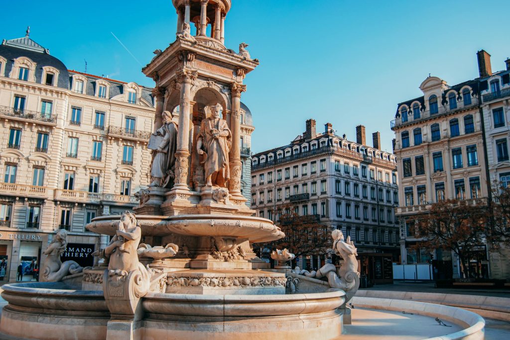 Elegant fountain at Place des Jacobins, Lyon, showcasing historic architecture in a vibrant urban setting.