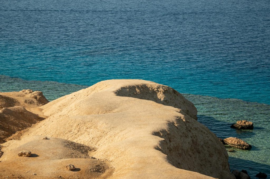 Golden sandstone formations by a vibrant blue sea under a clear summer sky.