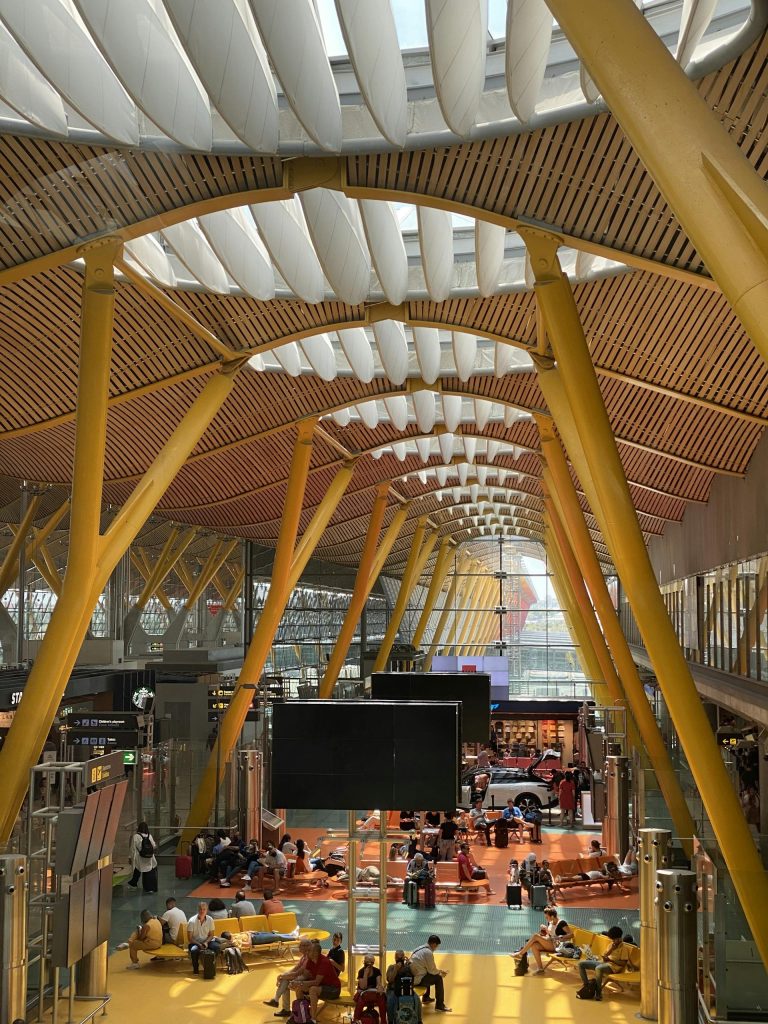 High angle view of Madrid Barajas Airport's modern terminal with people and striking architecture.