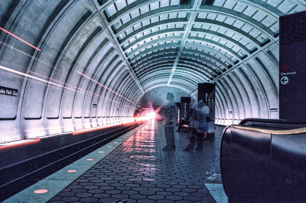 Long exposure shot of a busy Washington DC metro station, capturing movement and train lights.