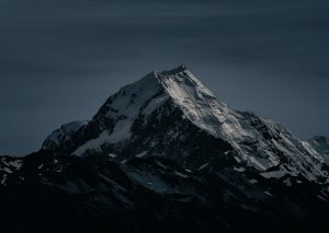 Majestic snow-covered peak in New Zealand captured at night, showcasing its striking silhouette.