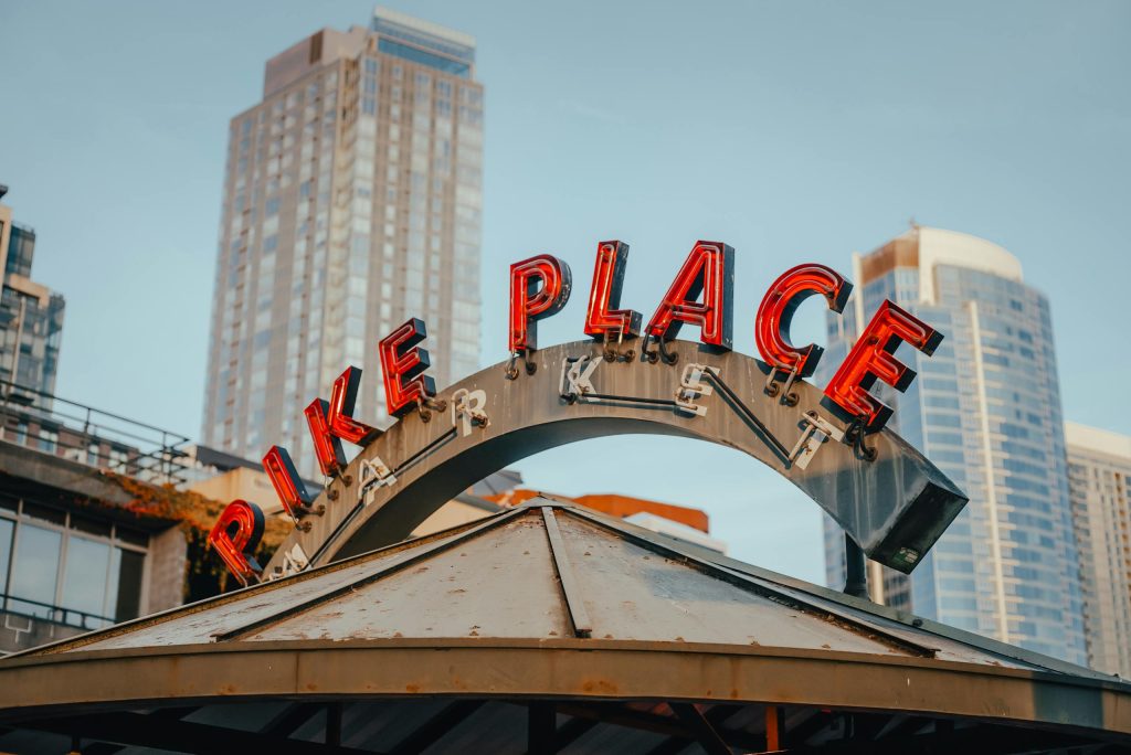 Pike Place Market sign with Seattle skyscrapers background, capturing the vibrant city vibe.