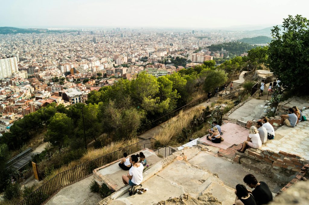 Relaxed tourists enjoy a panoramic view of Barcelona's skyline from Bunkers del Carmel.