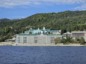 Scenic view of a historic monastery nestled on Mount Athos with lush greenery and oceanfront.