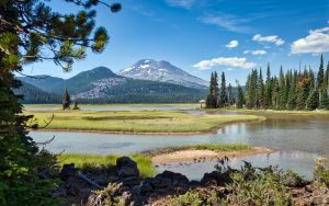 Scenic view of a tranquil lake surrounded by mountains and trees in Bend, Oregon.