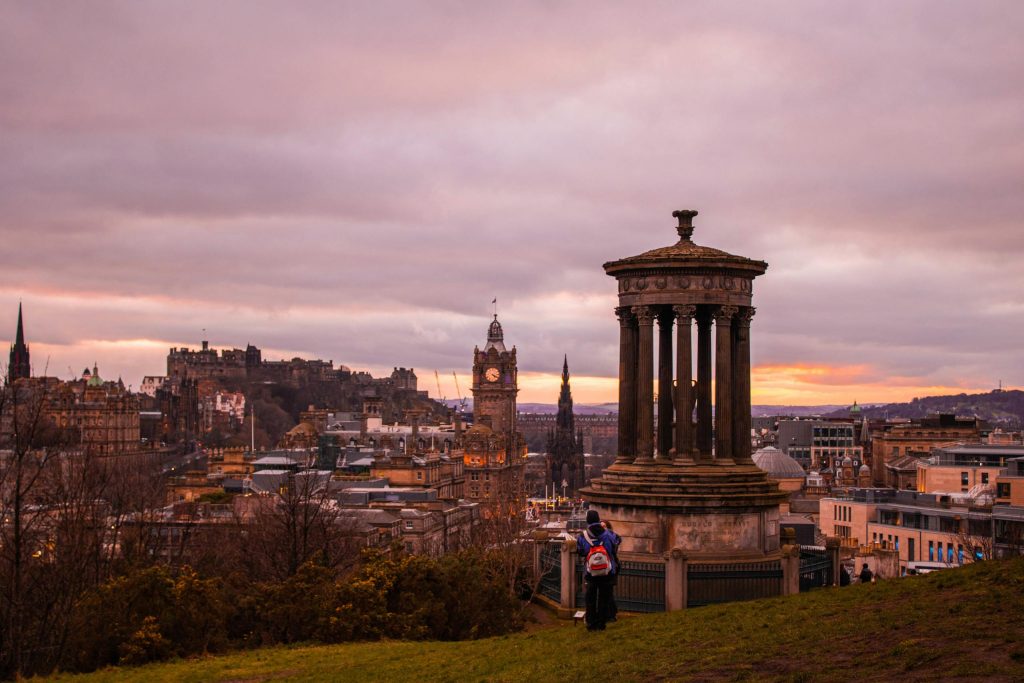 Scenic view of Edinburgh city skyline at sunset from Calton Hill, featuring historic architecture.