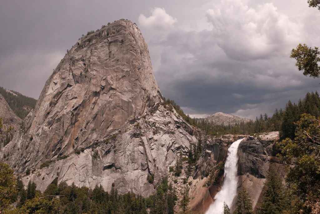 Scenic view of Liberty Cap and Nevada Fall under cloudy skies in Yosemite National Park.