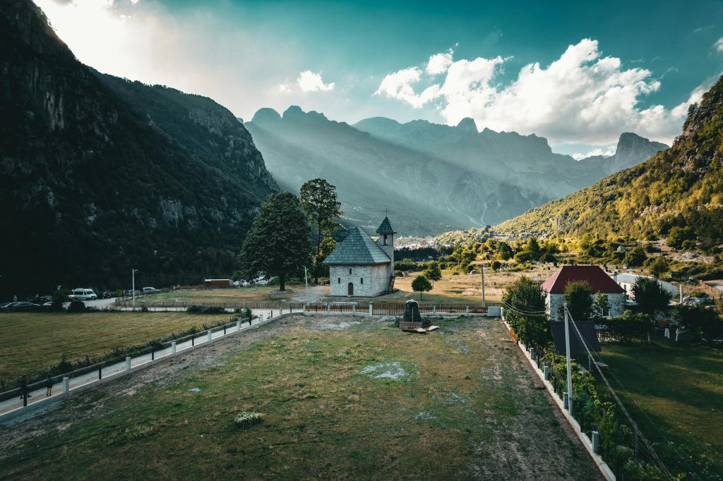 Scenic view of Theth village with mountains and historic church in Albania.